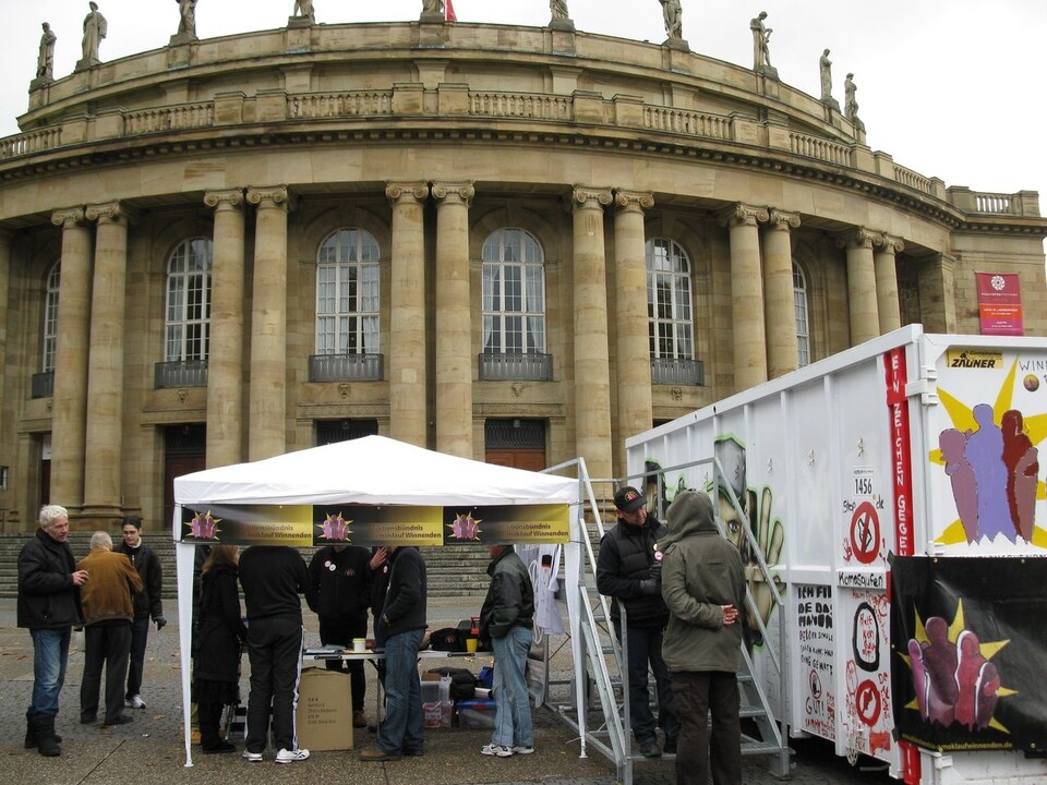 Auf dem Platz vor der Staatsoper in Stuttgart stehen Container und Infostand der AAW.