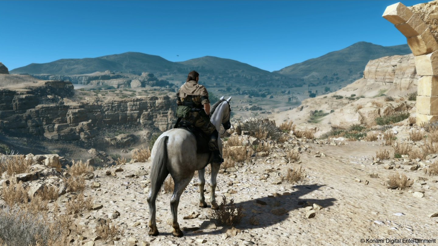 Metal Gear Solid 5Snake kann nicht nur per Jeep, Truck oder Panzer von A nach B kommen, sondern auch auf dem Pferd durch den Wüstenstaub galoppieren. Um ungesehen an Patrouillen vorbeizukommen, hängt er sich an die Seite seines haferbetriebenen Untersatzes.