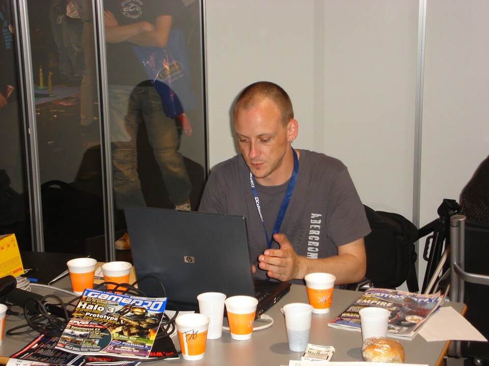 Games Convention 2007: Im gläsernen Redaktionsbüro werkelt Henry an Artikeln, während rundherum die Messe trubelt.