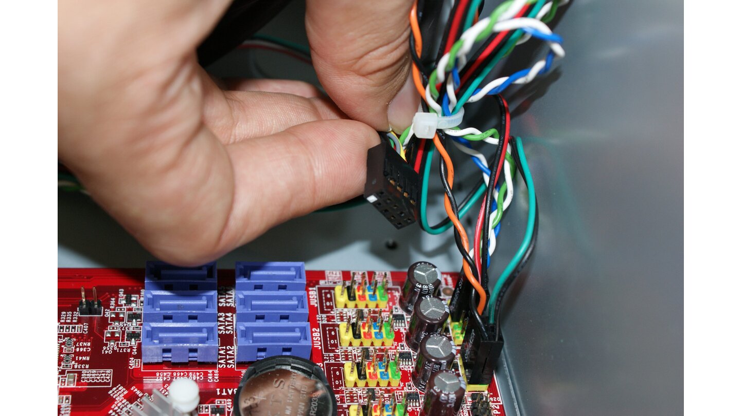 Die beiden USB-Ports an der Gehäusefront verbindet das als »USB« gekennzeichnete Kabel mit dem Pfostenstecker (rot markiert) auf dem Mainboard. Ein Kanal am Stecker ist blockiert, sodass der Anschluss nur in der korrekten Ausrichtung möglich ist.