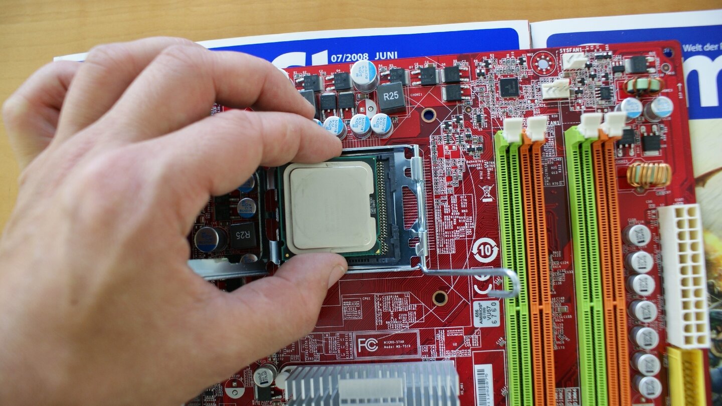 Nehmen Sie den Prozessor vorsichtig in die Hand, ohne die Kontakte auf der Unterseite zu berühren. Öffnen Sie den CPU-Sockel und legen Sie den Prozessor so hinein, dass die beiden Plastiknasen des Sockels in die Kerben des Prozessors passen.