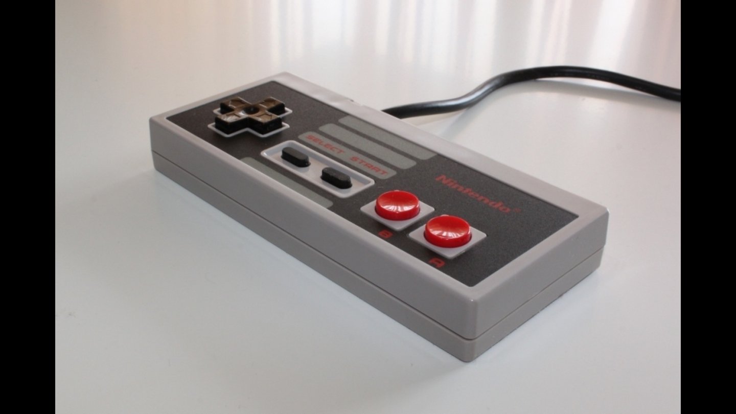 NES (Europa 1986): DER klassische Konsolen-Controller im heute weltbekannten, neuen Farbschema für den Westen. Das Steuerkreuz des NES-Controllers hat Nintendo patentiert. Die Gamepads von Sony und Microsoft müssen daher bis heute auf ein anderes Design zurückgreifen.
