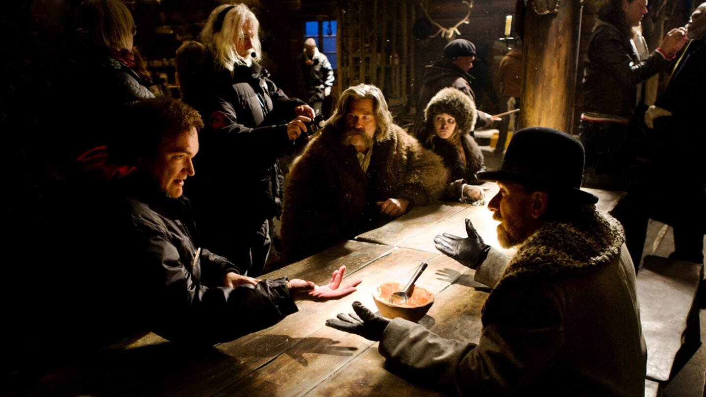 The Hateful 8Behind the Scenes: Regisseur Quentin Tarantino erklärt eine Szene. Am Tisch rechts: Tim Roth. Links: Kurt Russell und Jennifer Jason Leigh.