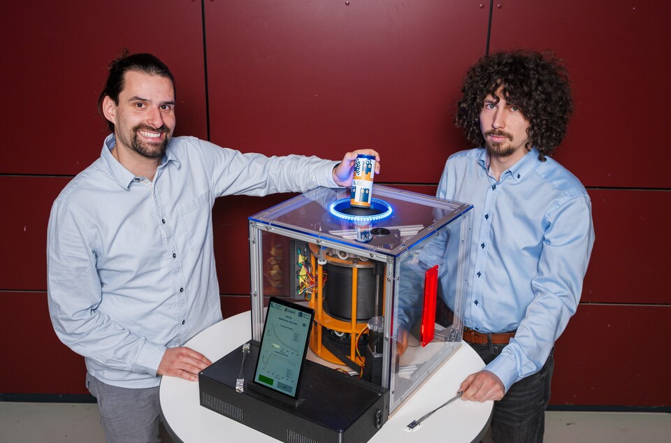 Der erste Kühlschrank-Prototyp, der Elastokalorik ausnutzt. Die Doktoranden Lukas Ehl (links) und Ivan Trofimenko (rechts) forschen mit an der Technologie. (Bildquelle: Oliver Dietze)