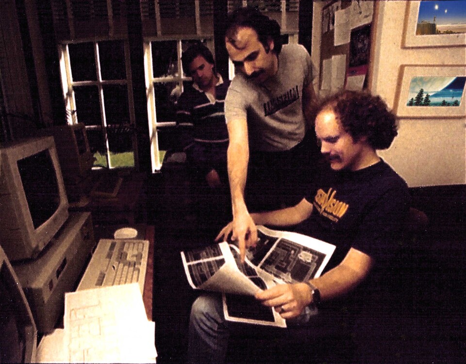 Das PR-Foto von 1989 zeigt das Projektleiter-Trio bei der Arbeit; im Hintergrund Ron Gilbert, in der Mitte Noah Falstein und vorne sitzend David Fox.
