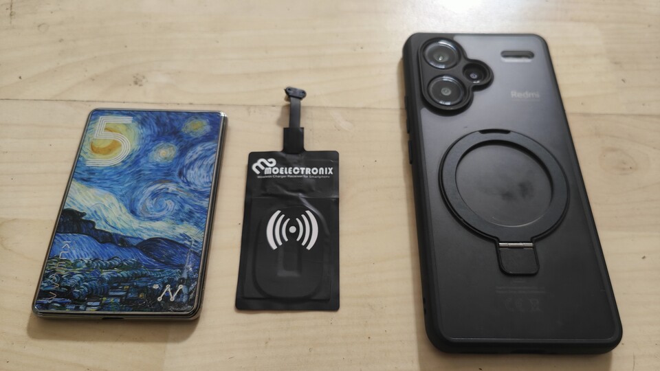 Links ist der 5.000 mAh-Akku, der kabellos arbeitet und magnetisch an der Hülle hält, mittig die induktive Ladespule, die zwischen Hülle und Handy kommt und rechts Handy mit Magsafe-Hülle.