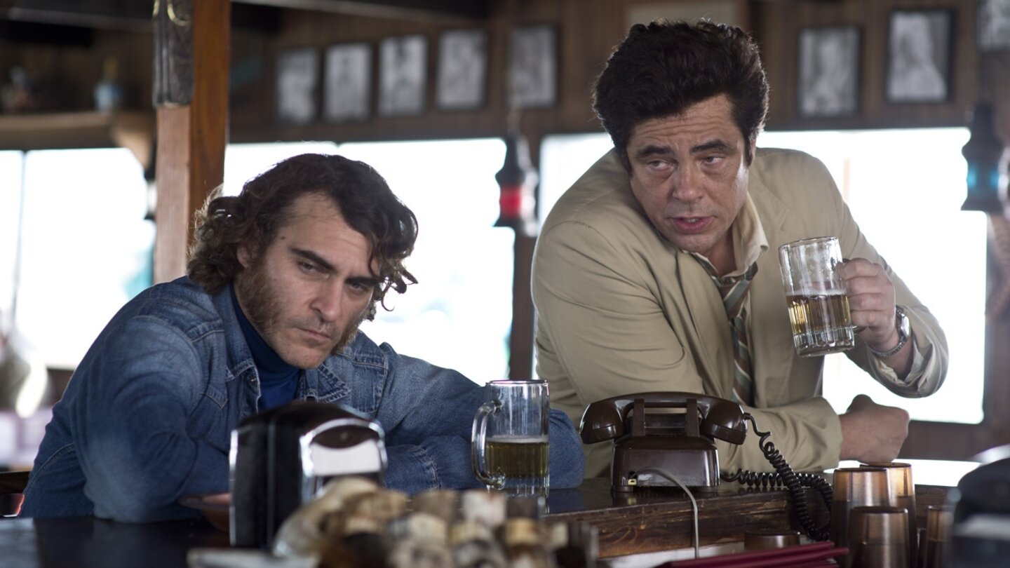 Inherent ViceBei einem kühlen Bierchen besprechen Sportello (Joaquin Phoenix) und sein Anwalt Sauncho Smilax (Benicio del Toro), wie sie den Doc aus der Schusslinie der Cops bringen.