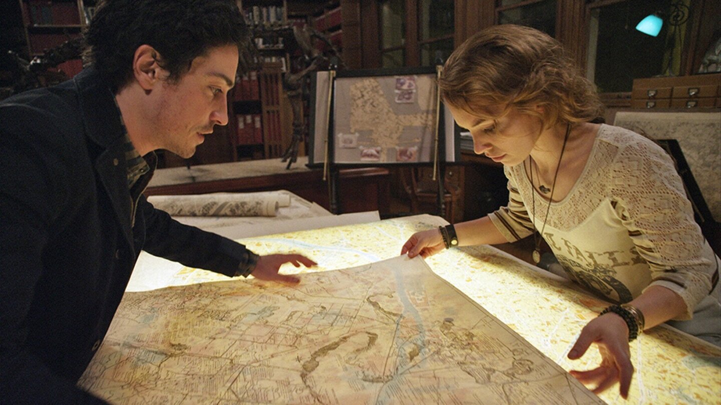 KatakombenScarlett und George suchen auf alten Karten nach dem idealen Eingang zu den Katakomben.