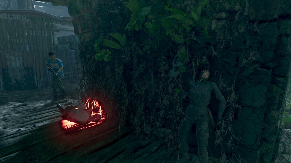 Während ein Feind von einer Leichenbombe angelockt wird, lauert Lara im Schatten der schlammbedeckten Wand.